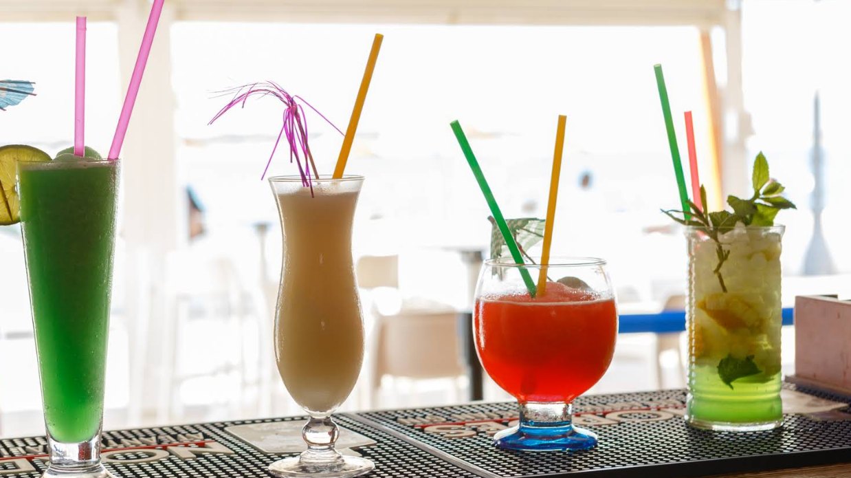 Cuatro cócteles en la barra: uno verde, uno de crema, un granizado rojo y un mojito