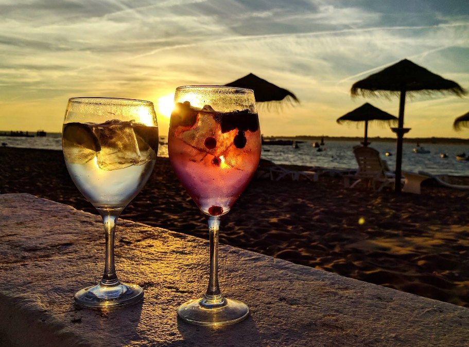 Dos copas de balón al atardecer sobre un murete, con sombrillas de paja a contraluz