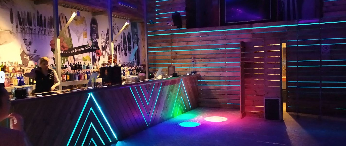 Interior del bar de noche con luces de neón de colores en la barra